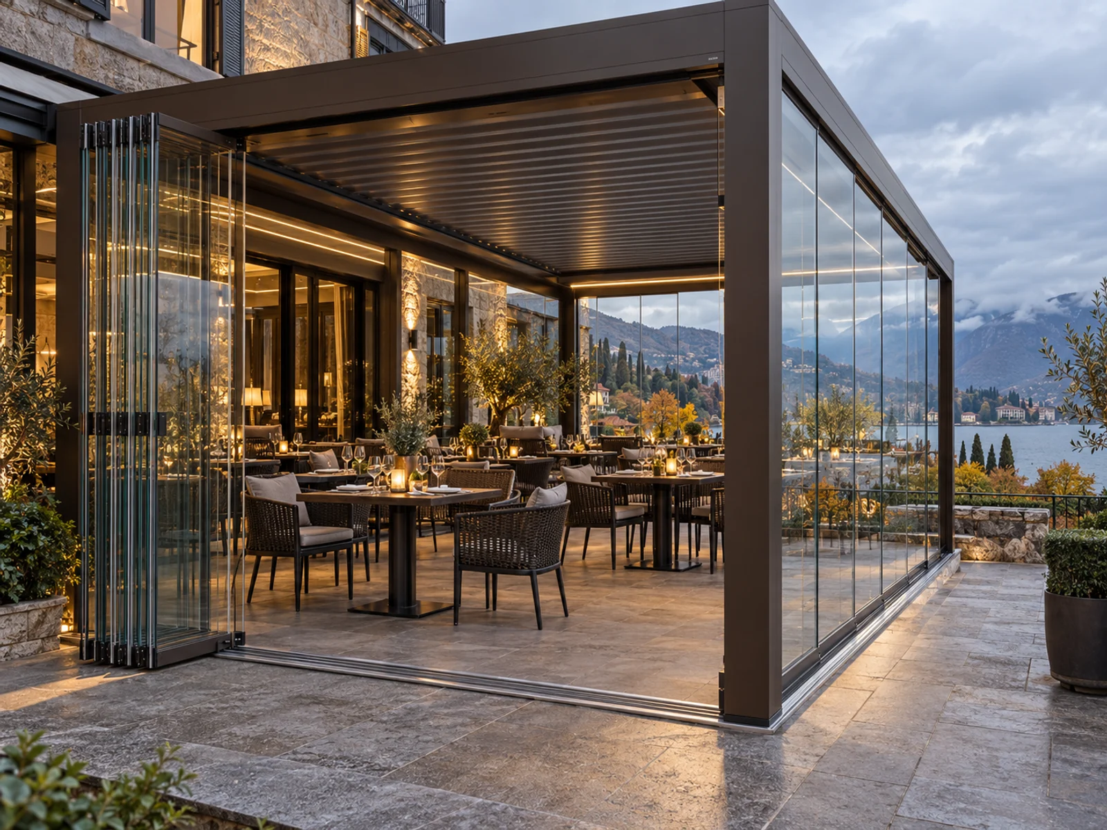 Dark bronze pergola with folding glass panels on a hotel terrace